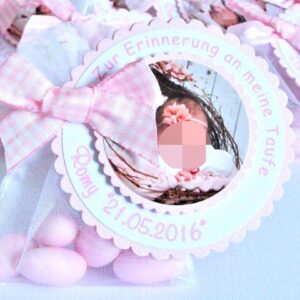 Gastgeschenk Mandelsaeckchen zur Taufe in rosa. Rund gewellter Anhaenger ist mit Taufdaten personalisiert. Mittig darin ist auf einem kleineren gewellten Label ein Foto des Taeufling angeordnet. Befestigt ist der Anhaenger mit einer rosa karierten Schleife, auf einem Organzasaeckchen in weiss, befuellt mit fuenf rosa Taufmandeln. Mandelspruch befindet sich rueckseitig. Design Lovely Times © KARTEN-DESIGN.at Nicki Heß