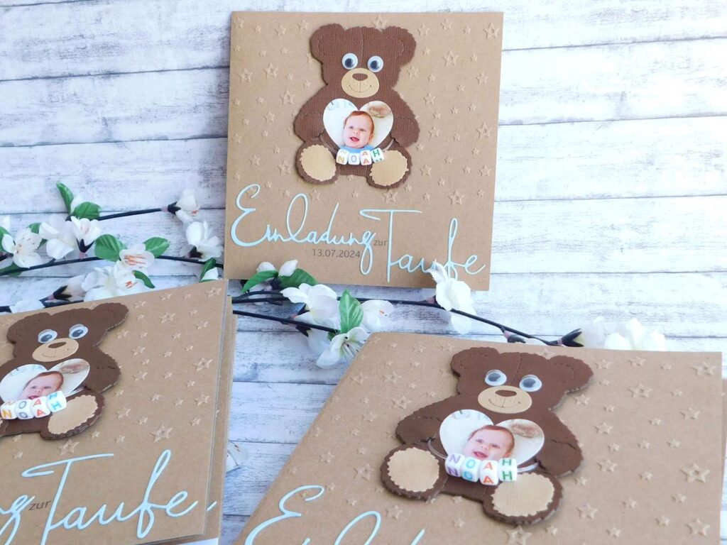 Taufeinladung aus Kraftkarton mit individueller Sternen-Prägung, süßem Teddy-Bären mit Kulleraugen & Foto eines Babys in Herzform darin. Kleine bunte Buchstabenwürfel mit dem Namen des Babys zieren den Teddy. Darunter ist der Schriftzug "Einladung zur Taufe" aus farbigen blauen Papier gestanzt und auf der Taufkarte befestigt. © KARTEN-DESIGN.at | Nicki Heß