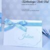 Tischkarte zur Taufe in weiß mit Gästename auf gewellten Anhänger, dekoriert mit schönem blauen Satinband. © KARTEN-DESIGN.at